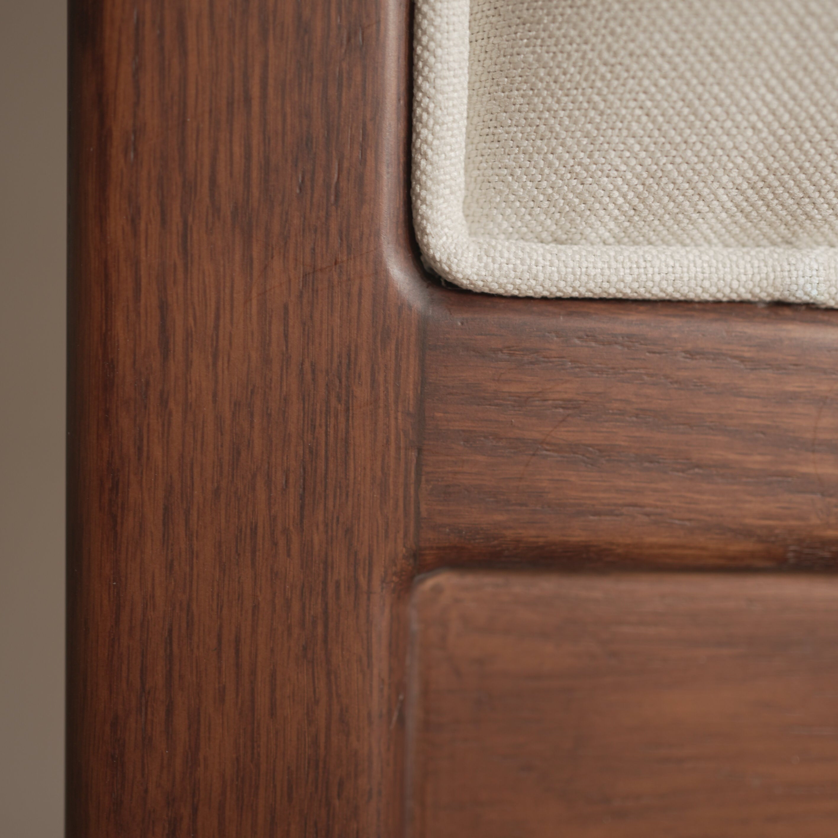 Close-up of a wooden headboard with a textured fabric panel.